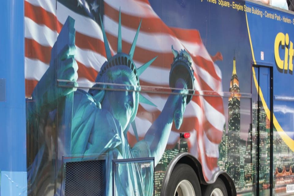 Statue of liberty and American flag and empire state of building behind painted on a large vehicle 