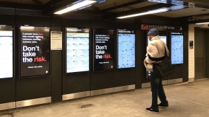 Subway station on 23rd street of FM line and a guy is standing reading digital information board